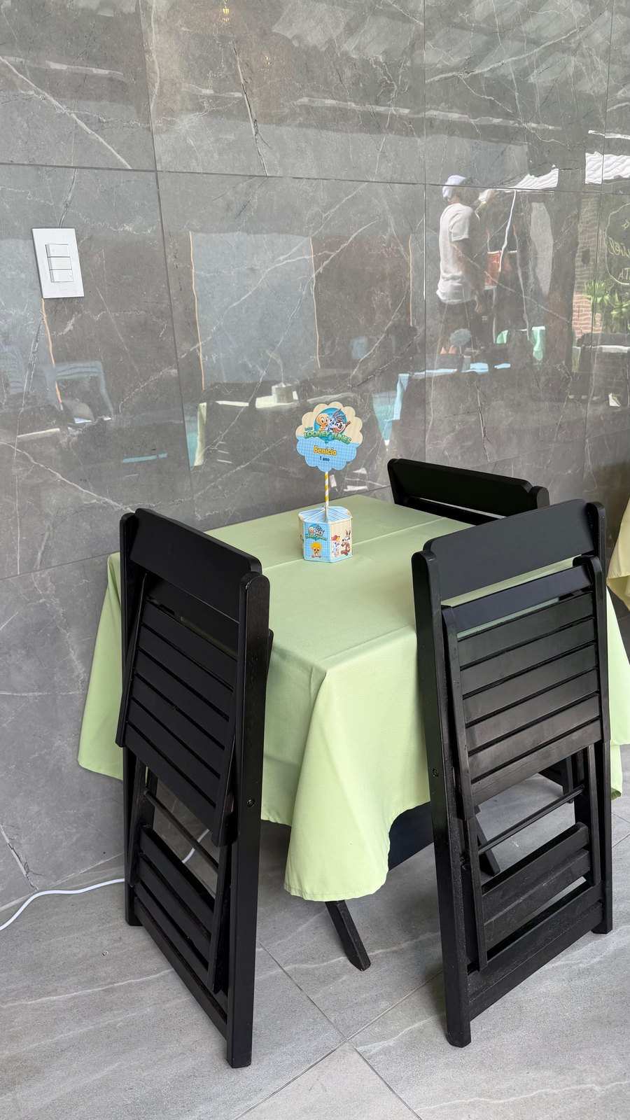 Mesa com toalha verde, cadeiras pretas e centro de mesa temático